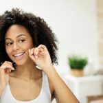 beautiful woman flossing her teeth in the mirror