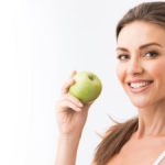 attractive woman holding an apple and smiling